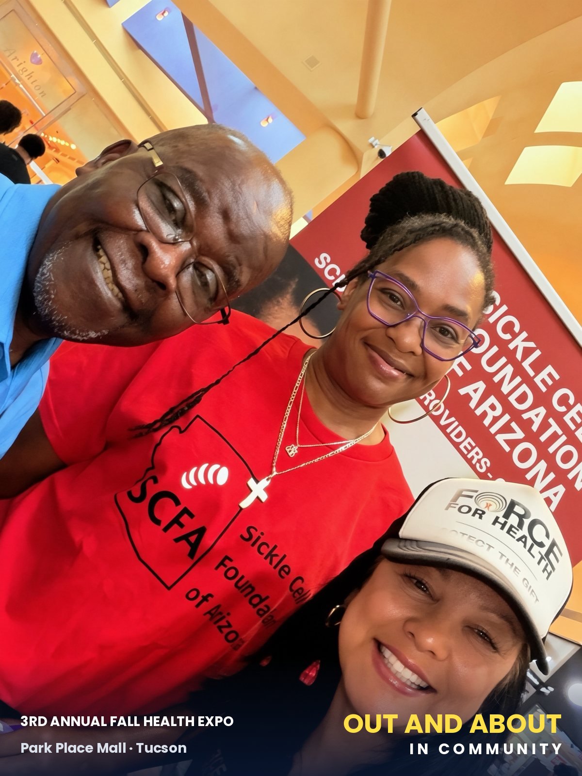 Coach Lucy with Moses Akpan and Akilah Gilbert in front of the Sickle Cell Foundation of Arizona banner.